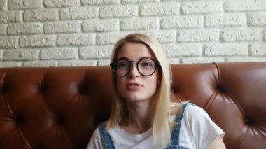 Deri kanepede oturan kız konuşuyor