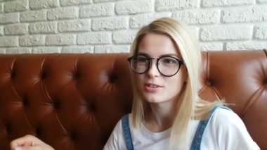 Deri kanepede oturan kız konuşuyor