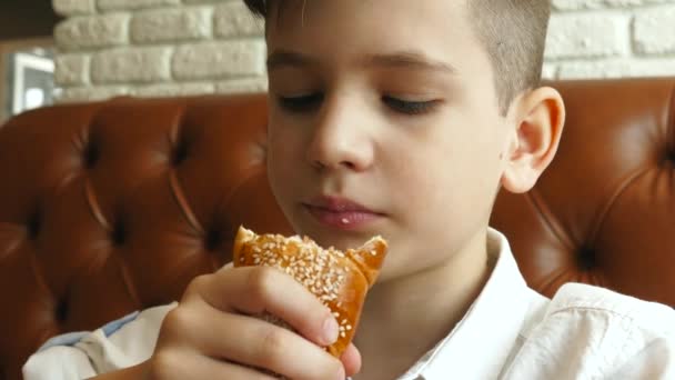 Niño comiendo el perrito caliente en la cafetería — Vídeo de stock