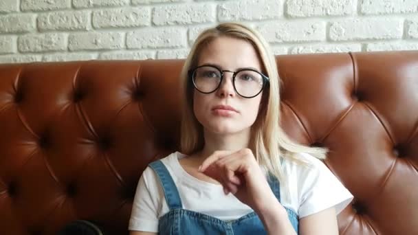 Dziewczynka flirty siedzący na skórzanej sofie — Wideo stockowe