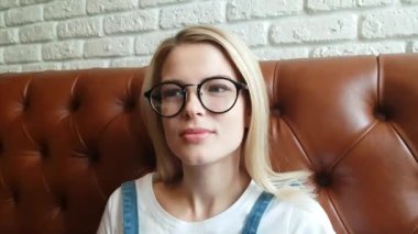 Deri kanepede oturan kız konuşuyor