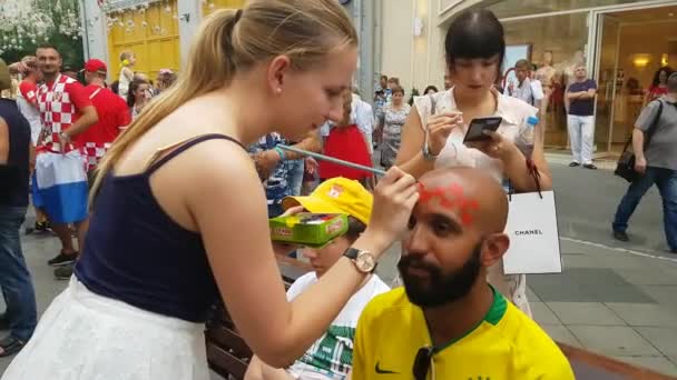 Mädchen malen Fahnen ins Gesicht von Fußballfans — Stockvideo