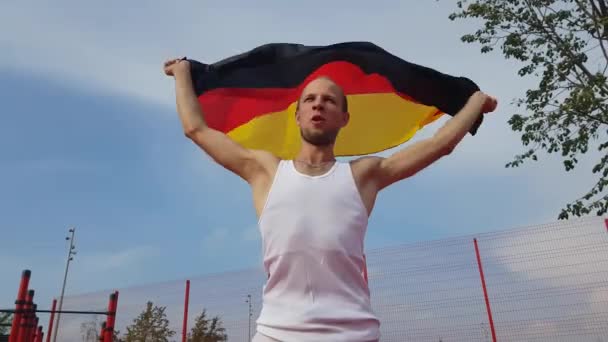 Joven sosteniendo bandera nacional alemana en el cielo con dos manos — Vídeo de stock