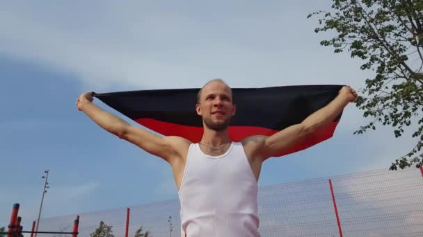 Ung Man håller tysk flagga till himlen med två händer — Stockvideo
