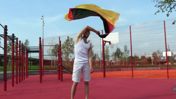 Junger Mann hält deutsche Nationalflagge mit zwei Händen in den Himmel — Stockvideo