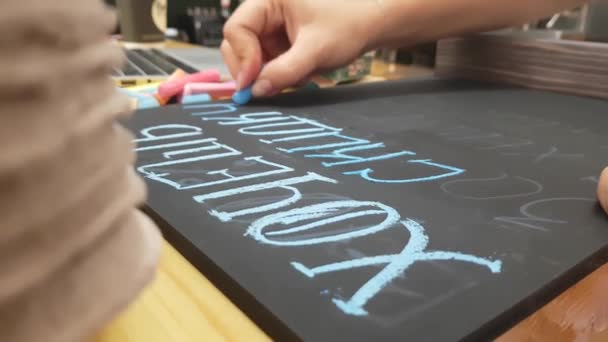Flickan skriver krita på en svart tavla — Stockvideo