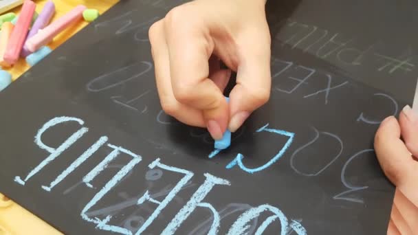 Flickan skriver krita på en svart tavla — Stockvideo