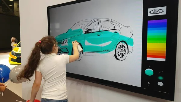 Uma menina pinta um carro em um quadro interativo — Fotografia de Stock