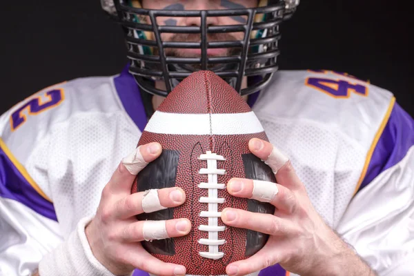 Boll för amerikansk fotboll framför fotbollsspelare ansikte — Stockfoto