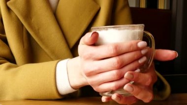 Kadın kahve Latte gelen cam fincan yakın yukarıda tut