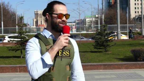 Reporter met een microfoon die een vest draagt — Stockvideo