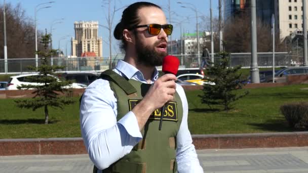 Reporter met een microfoon die een vest draagt — Stockvideo