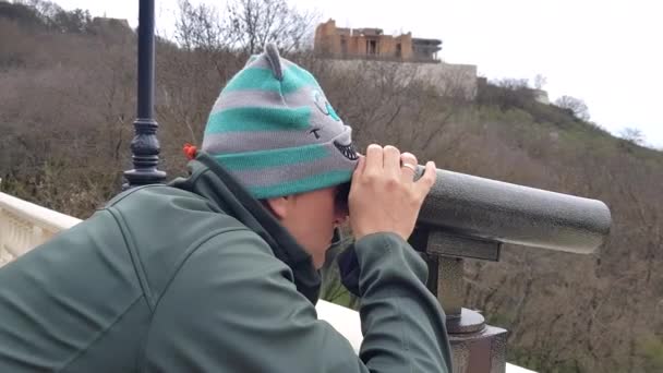 Hombre mirando a través de prismáticos a la ciudad desde el mirador en la montaña — Vídeos de Stock