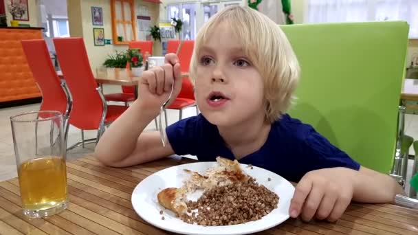 O menino no café para um prato de mingau de trigo mourisco — Vídeo de Stock