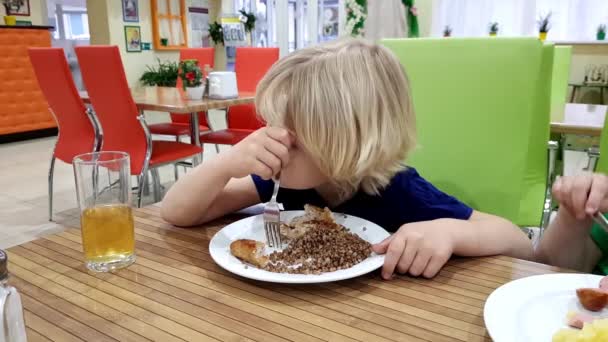 Мальчик в кафе за тарелкой гречневой каши — стоковое видео