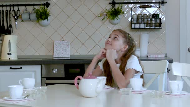 Schattig blond meisje zittend aan de keuken tafel — Stockvideo