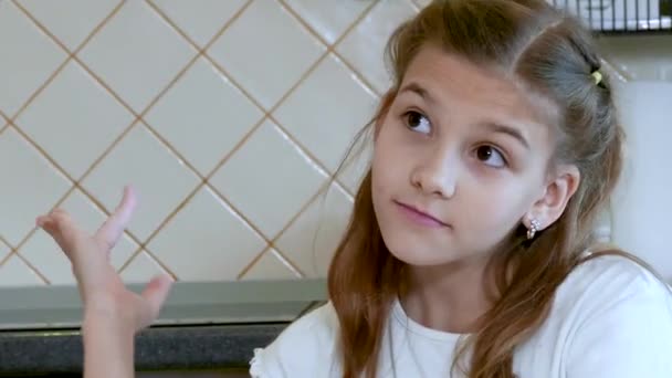 Aranyos szőke lány ül a konyhaasztalnál — Stock videók