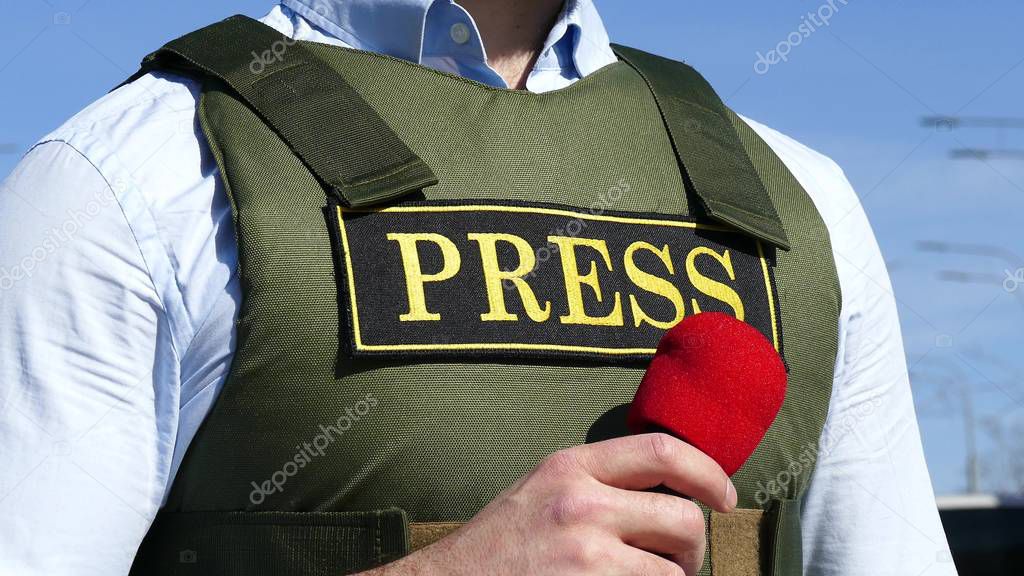 Hand with a microphone on the background of a bulletproof vest with an inscription press