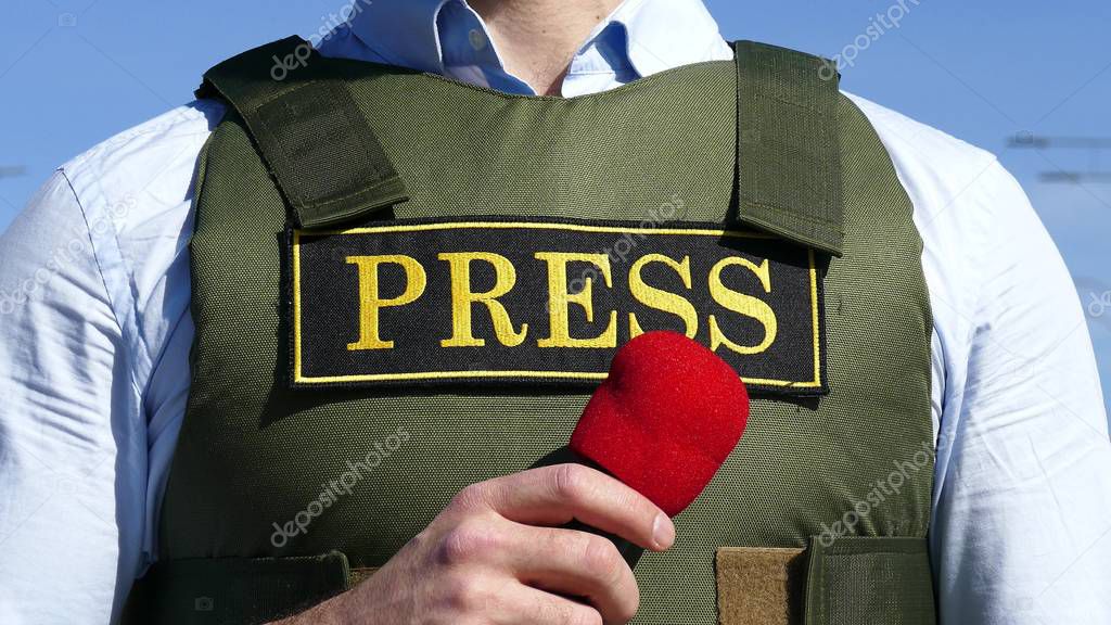 Hand with a microphone on the background of a bulletproof vest with an inscription press