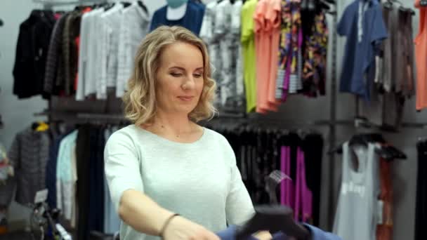 Attraktive junge Frau beim Kleiderkauf — Stockvideo