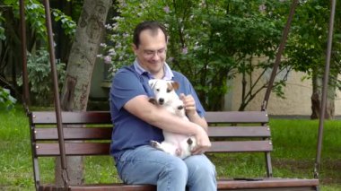 Parkta köpek yavrusuyla oturan adam