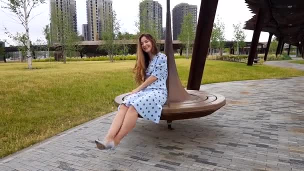 Красавица кружится на скамейке в парке — стоковое видео