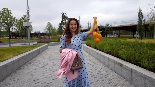 Csinos nő tartsa narancs a húros zsákba — Stock videók