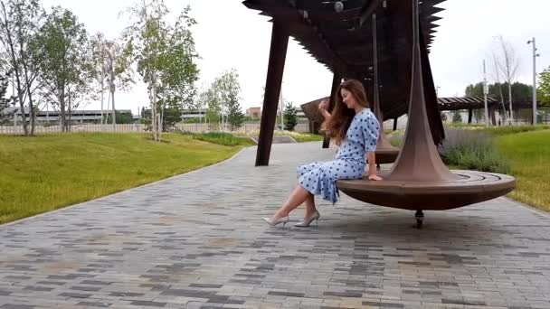 Гарненька жінка прядиться на лавці в парку — стокове відео