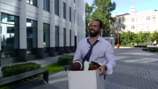 Positiv man går ner på gatan med en låda med saker från kontoret. — Stockvideo