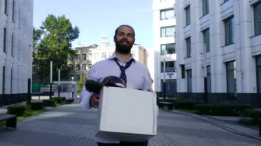 Pozitif adam ofiste şeyler ile bir kutu ile sokakta yürüyor.
