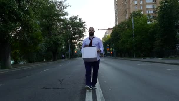 Triste hombre con la caja va en el medio de la carretera . — Vídeos de Stock