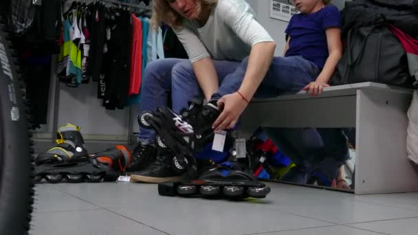 Kopers maatregel rolschaatsen voor een kind in de winkel. — Stockvideo