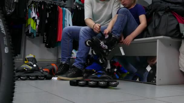 Kopers maatregel rolschaatsen voor een kind in de winkel. — Stockvideo