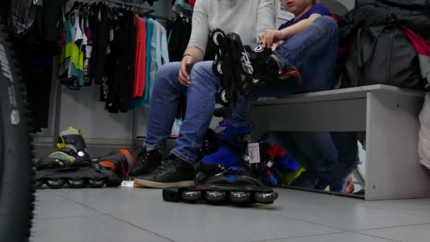 Os compradores medem patins para uma criança na loja . — Vídeo de Stock