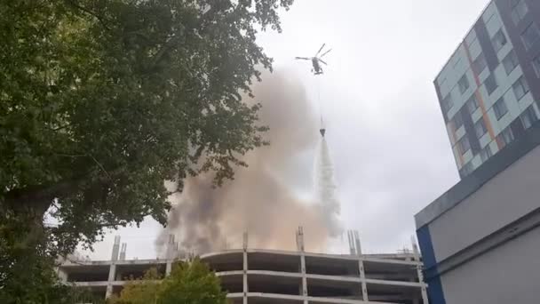 Brandweerman helikopter druppels water om een brand te blussen op een gebouw — Stockvideo