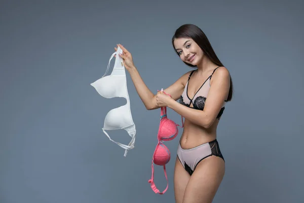 Reggiseno rosso e beige nelle mani di una donna bruna . — Foto Stock