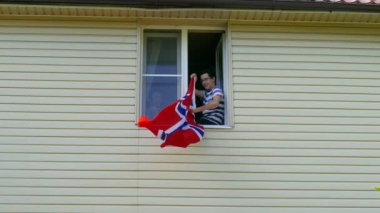 Evdeki pencerede bayrak sallayan gençler