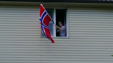 Evdeki pencerede bayrak sallayan gençler