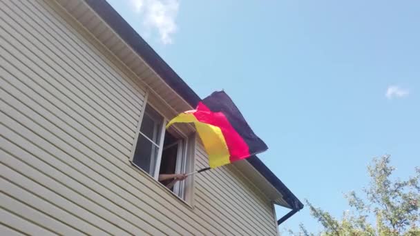 Jovens acenando uma bandeira em uma janela em casa — Vídeo de Stock