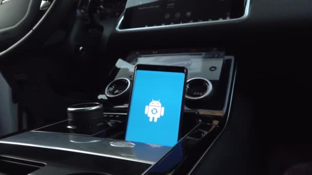 Android значок логотипу робот на екрані смарт-телефону під час установки оновлення в автомобілі — стокове відео