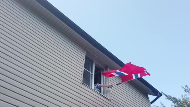 Jonge mensen zwaaien een vlag in een venster — Stockvideo