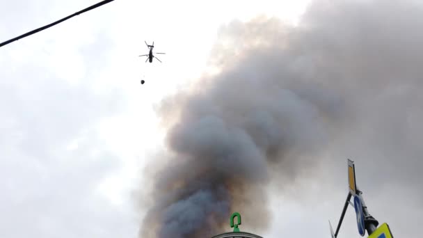 Пожарный вертолет сбрасывает воду, чтобы потушить пожар на здании — стоковое видео