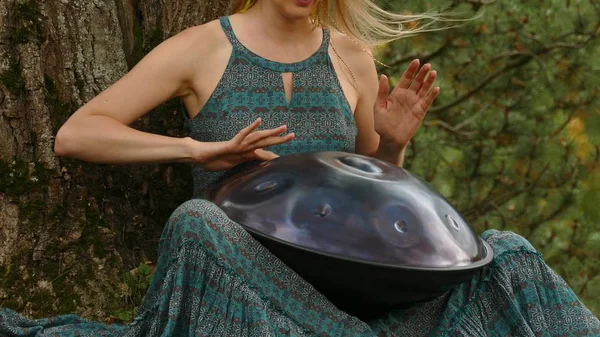 Popular, modern hang musical instrument in the hands of a beautiful blonde in park. — Stock Photo, Image