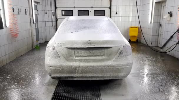Washerman está rociando el agua por el nebulizador en el cuerpo del coche en una caja de lavado del coche — Vídeos de Stock