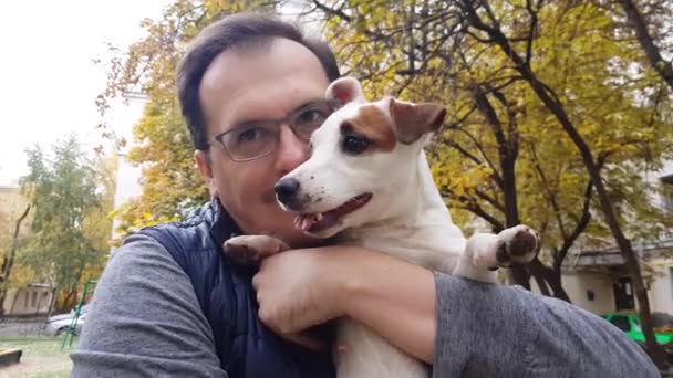 Weißer Welpe mit erwachsenem Mann im Freien — Stockvideo