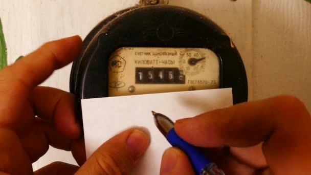 사람은 오래 된 전기 계량기의 측정치를 기록한다 — 비디오