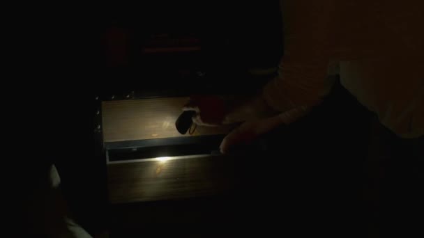 Человек с фонариком достает устройство из ящика — стоковое видео