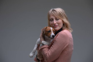 Yavru köpek kameraya bakar ve sahibinin elleriyle oturur.