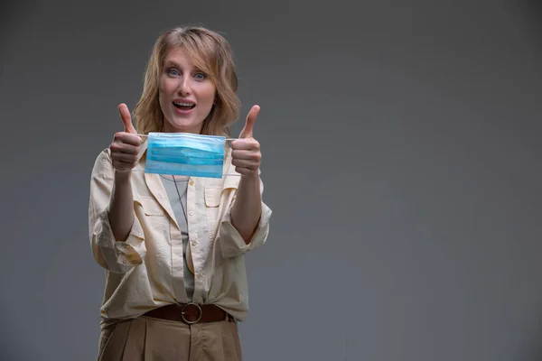 Cabeza retrato atractiva mujer rubia mirando cámara celebrar médico o quirúrgico color azul mascarilla — Foto de Stock