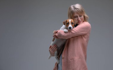 Yavru köpek kameraya bakar ve sahibinin elleriyle oturur.